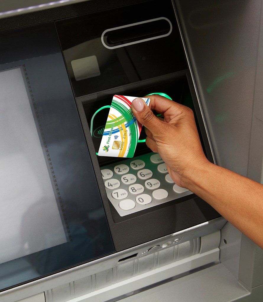 Lady holding a First Citizens Visa Debit Card at an ATM.